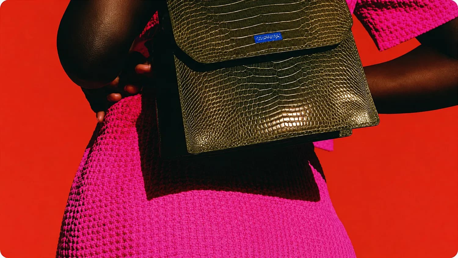 Olive croc-embossed bag against a scarlet backdrop