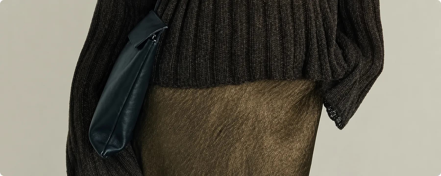 Detail of a chunky knit sweater and leather shoulder bag