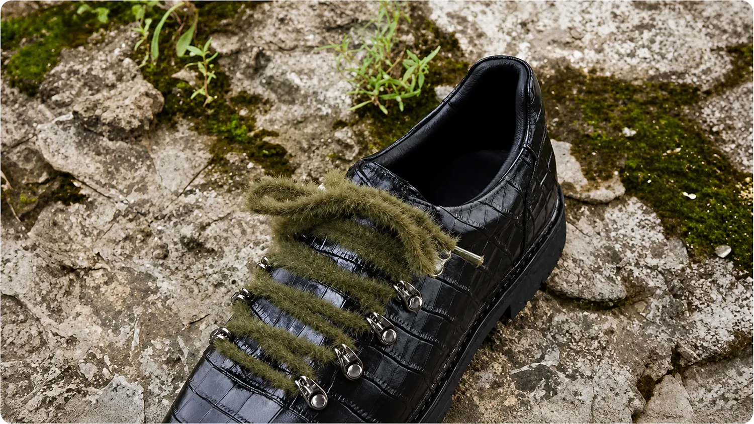 Black croc leather sneaker on mossy rock