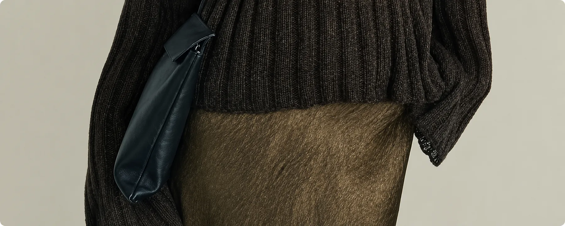Detail of a chunky knit sweater and leather shoulder bag